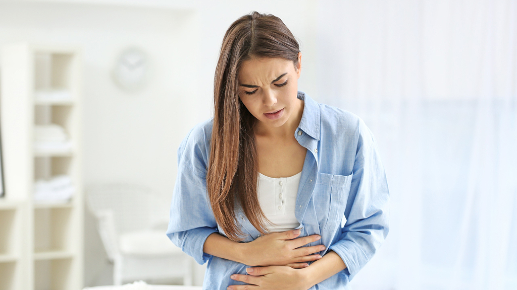 Mujer con expresión de dolor y manos sobre su vientre